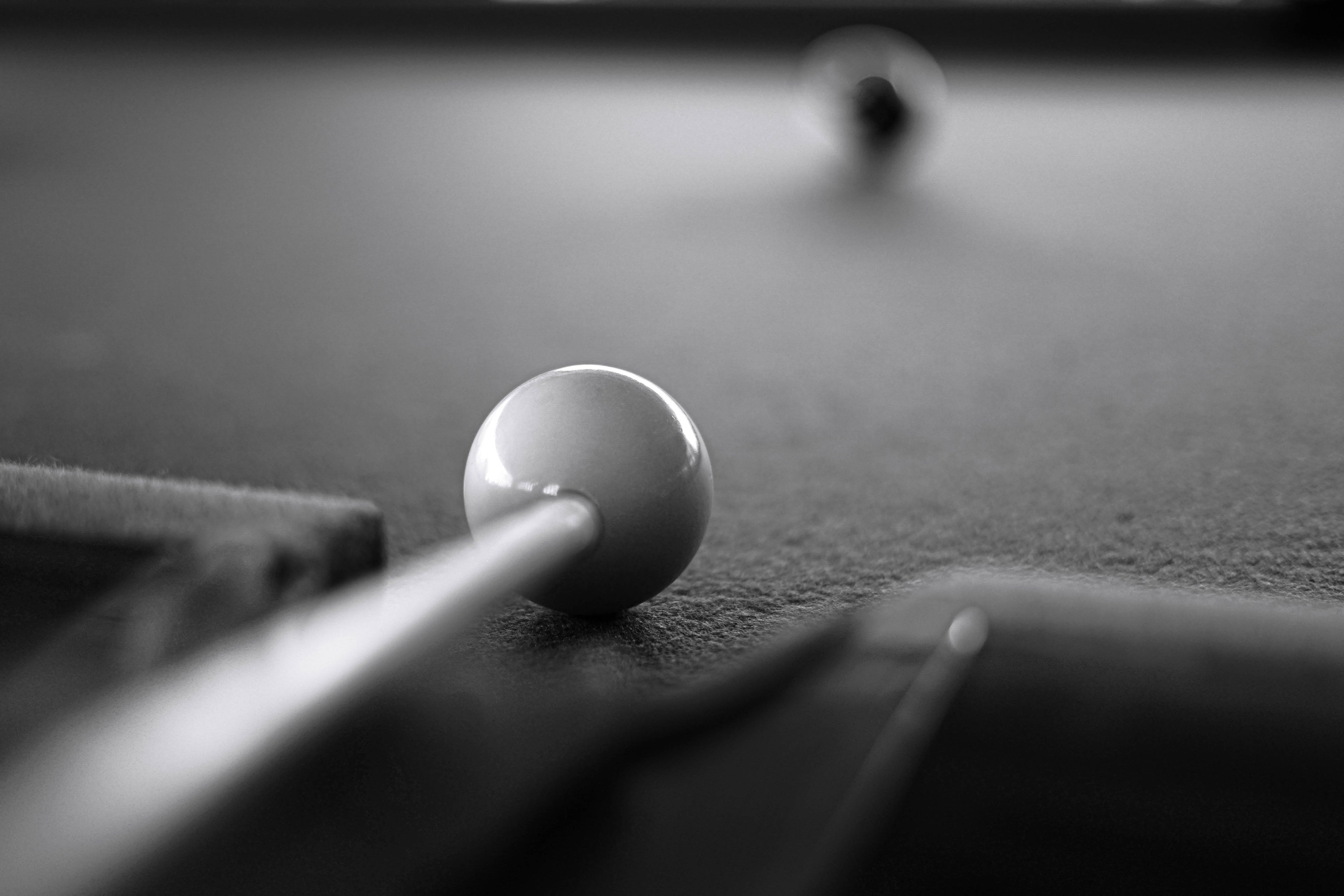 black and white picture of a billiard cue that going to hit a cue ball